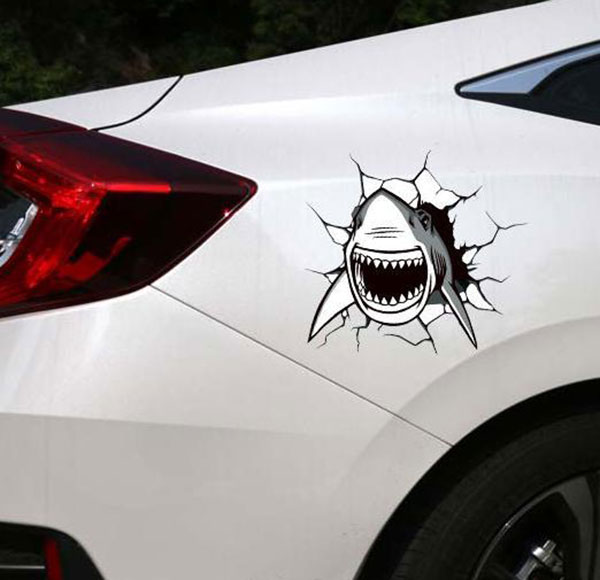 Photo of a decal showing a shark breaking out of dent in the side of a car