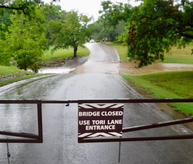 Photo: Bridge closed sign with overflowing creek in background