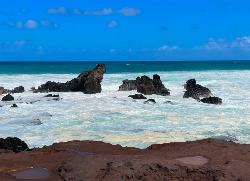 Photo: rocks jutting out of foaming surf at Ho'okipa Beach Park in Maui, HI