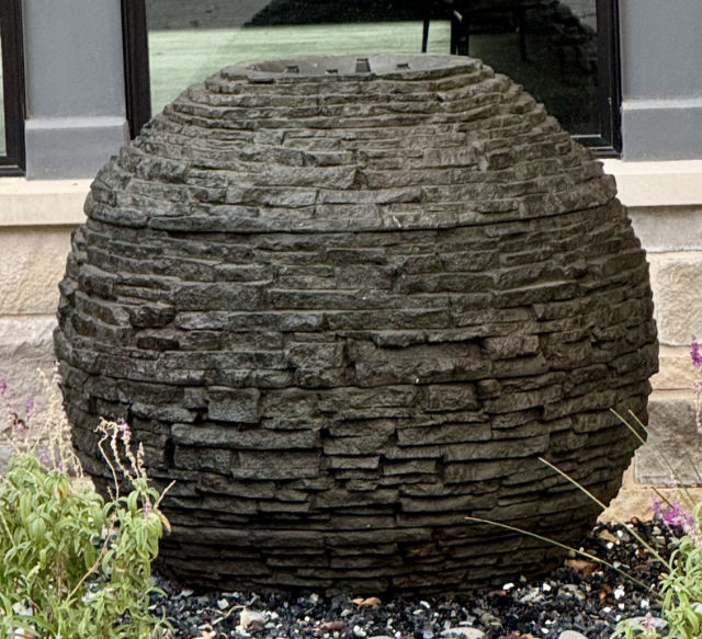 Photo of a globe-shaped water fountain in front of a house