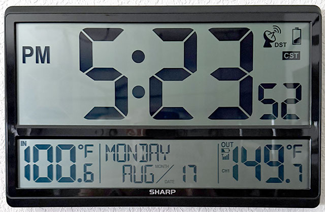 Wall-mounted thermometer showing 100º F indoors and 149.7º outdoors